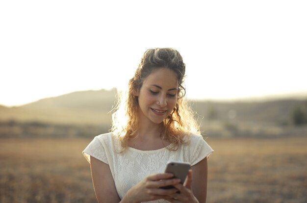 lächelnde junge Frau, die auf ihr Telefon schaut