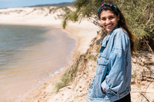 Lächelnde junge Frau, die auf Küste steht