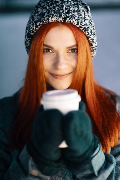 Lächelnde junge Frau, die draußen eine Tasse Kaffee genießt