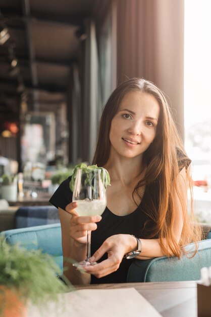 Lächelnde junge Frau, die Glas Getränk im Restaurant hält