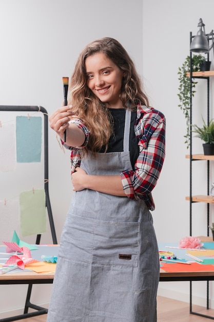 Lächelnde junge Frau, die schwarzen Malerpinsel zeigt