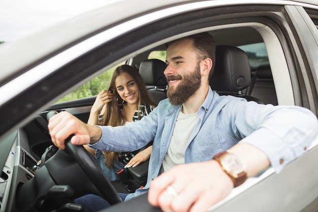 Lächelnde junge Frau, die seinen Freund fährt Auto betrachtet