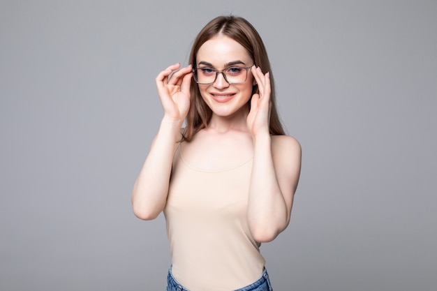 Lächelnde junge Frau mit Brille über graue Wand