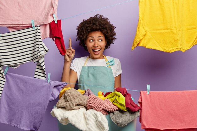 Lächelnde junge Frau mit einem Afro, der mit Wäsche im Overall aufwirft