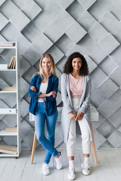 Kostenloses Foto lächelnde junge frauen, die im büro stehen