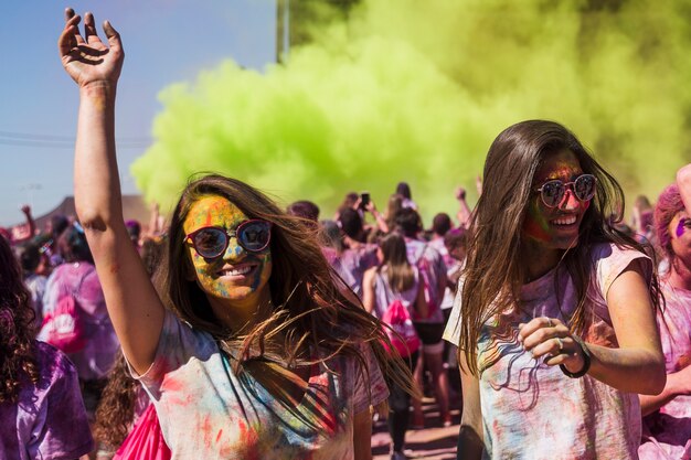 Lächelnde junge Frauen, die in das holi Festival tanzen