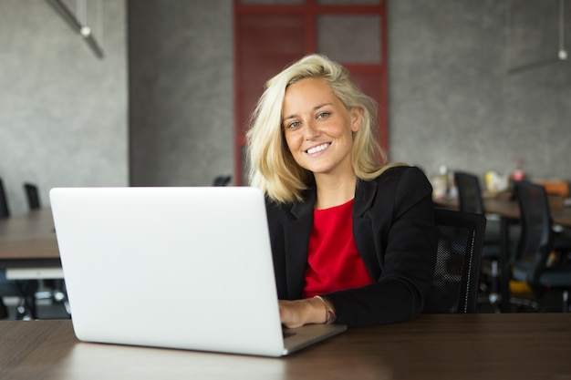 Kostenloses Foto lächelnde junge geschäftsfrau, die am laptop arbeitet