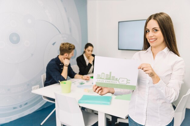 Lächelnde junge Geschäftsfrau, die energiesparendes Konzept im Büro zeigt