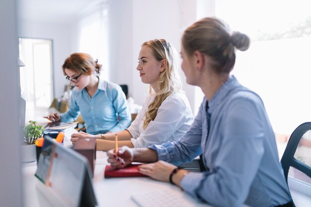 Lächelnde junge Geschäftsleute, die in Folge sitzen, arbeiten im Büro