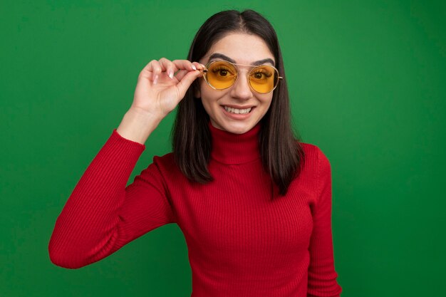 Lächelnde junge hübsche kaukasische Frau, die eine Sonnenbrille trägt und greift