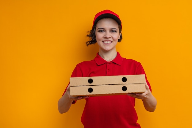 Lächelnde junge hübsche Lieferfrau hält Pizzakartons