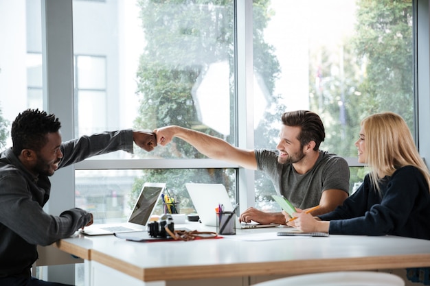 Lächelnde junge Kollegen, die im Büro Coworking sitzen