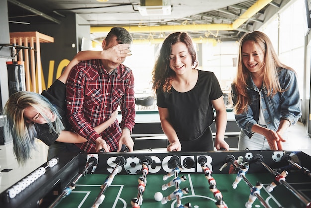 Kostenloses Foto lächelnde junge leute, die tischfußball spielen, während sie drinnen sind