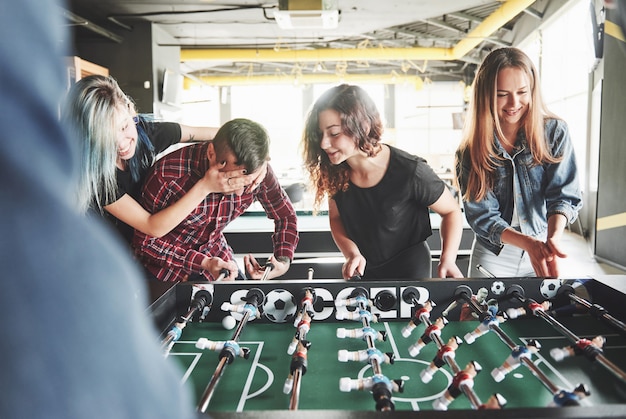 Kostenloses Foto lächelnde junge leute, die tischfußball spielen, während sie drinnen sind