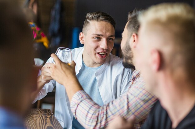 Lächelnde junge Männer, die das Getränk mit Freunden genießen