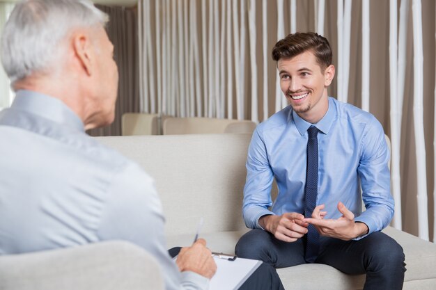 Lächelnde junge Mitarbeiter im Gespräch mit Business Leader