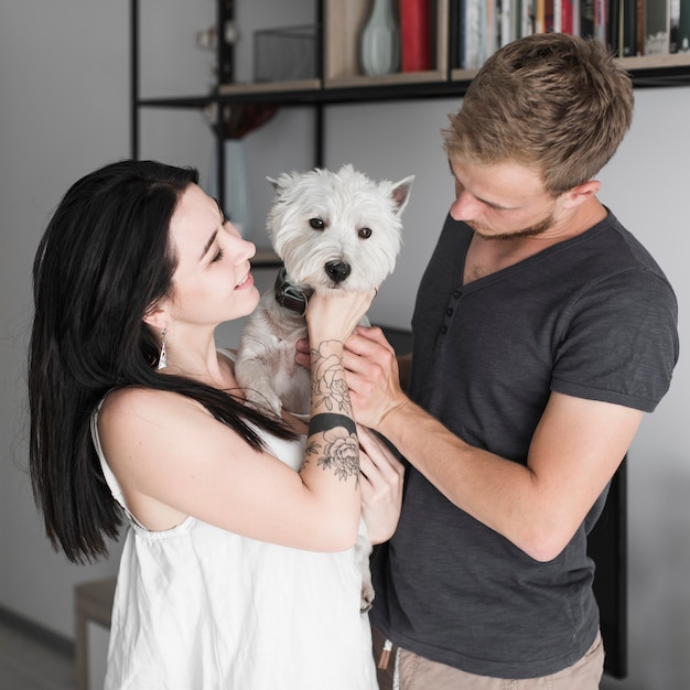 Lächelnde junge Paare, die ihren weißen Hund lieben