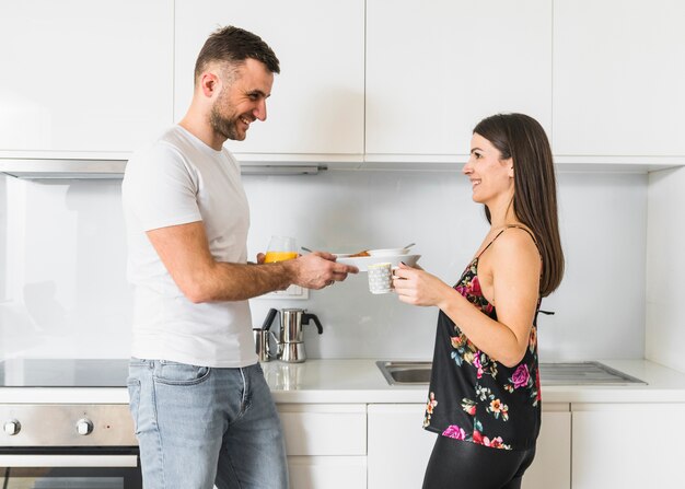 Lächelnde junge Paare, die in der Küche frühstücken