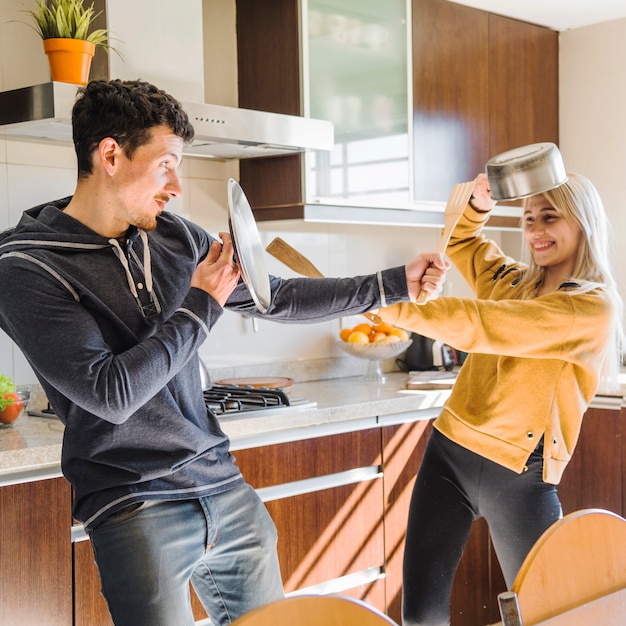 Kostenloses Foto lächelnde junge paare, die mit gerät in der küche kämpfen