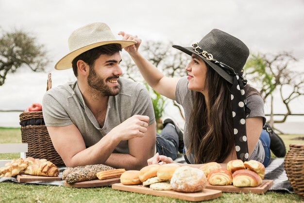 Lächelnde junge Paare, die modernen Hut am Picknick tragen