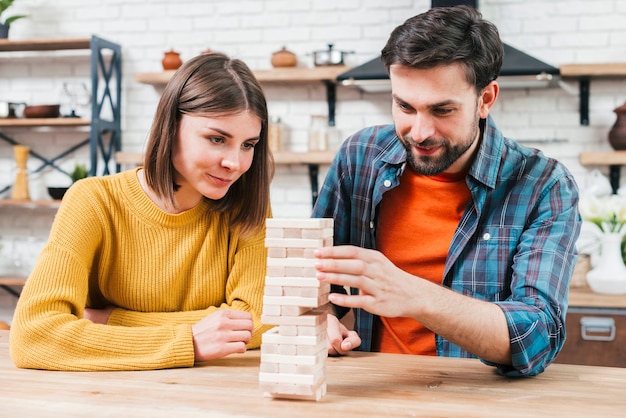 Lächelnde junge Paare, die zu Hause das Holzklotzturmspiel spielen