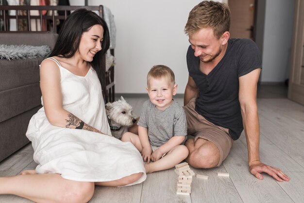 Lächelnde junge Paare, die zu Hause mit seinem Sohn und Hund spielen