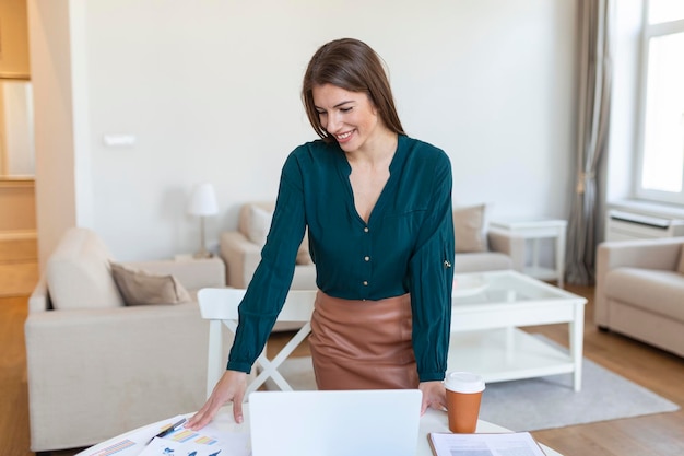 Lächelnde junge weibliche Angestellte stehen am Schreibtisch im Büro und schauen in die Ferne, denken oder visualisieren den beruflichen Erfolg. Glückliche Geschäftsfrau plant oder träumt am Arbeitsplatz Business-Vision-Konzept