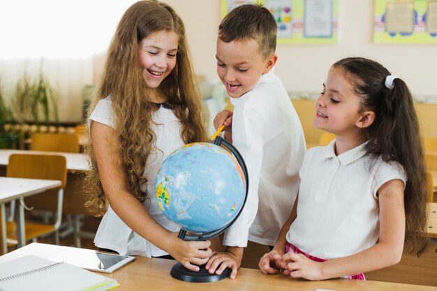 Lächelnde Kinder, die Spaß mit Globus haben