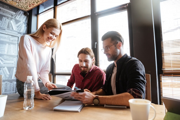 Lächelnde Kollegen, die im Büro sitzen und arbeiten