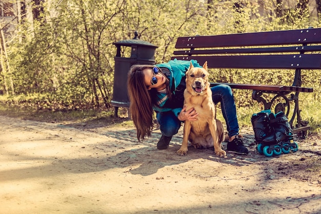 Kostenloses Foto lächelnde lässige frau mit ihrem braunen pitbull-hund in einem park.