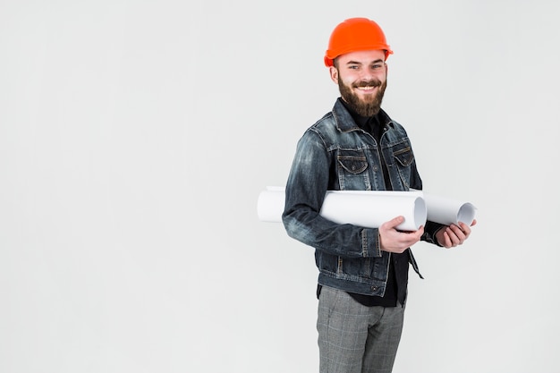 Lächelnde männliche Ingenieurholding rollte herauf Plan gegen weißen Hintergrund
