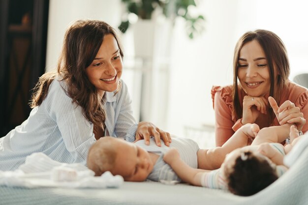Lächelnde Mütter spielen mit ihren Babys und genießen die Mutterschaft zu Hause