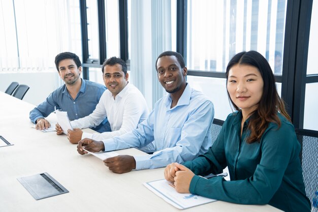 Lächelnde multiethnische Manager, die mit Diagrammen in der Chefetage arbeiten.