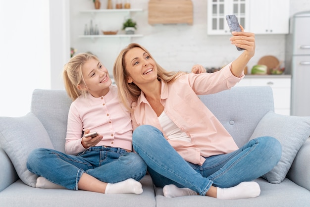 Lächelnde Mutter und Tochter, die selfies nehmen