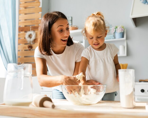 Lächelnde Mutter und Tochter, die Teig zubereiten