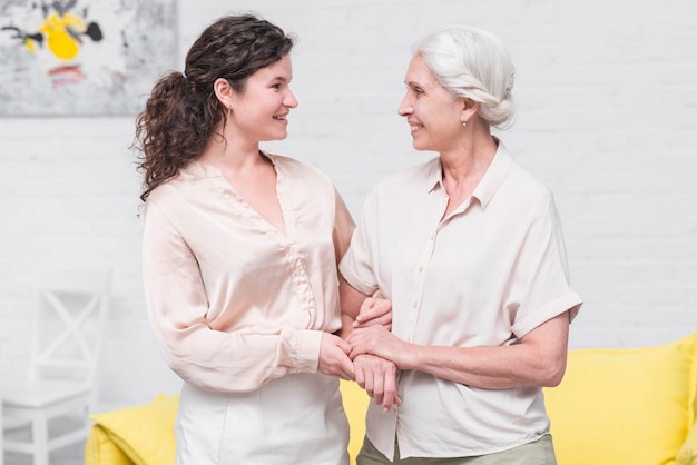 Lächelnde Mutter und Tochter, die zu Hause die Hand des anderen hält