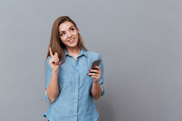 Lächelnde nachdenkliche Frau im Hemd mit Telefon