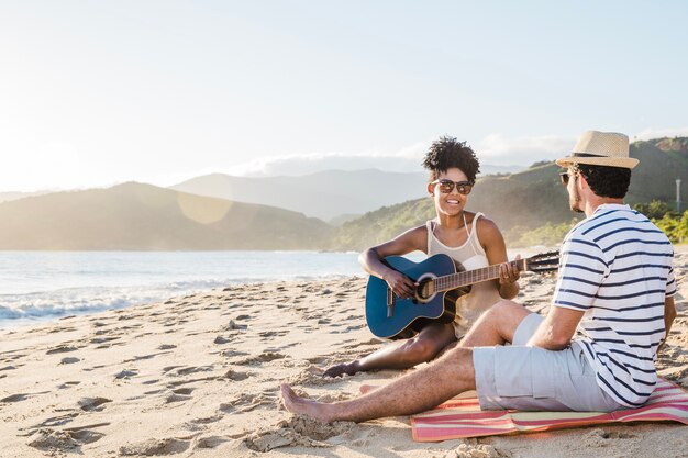 Lächelnde Paar mit Gitarre am Strand