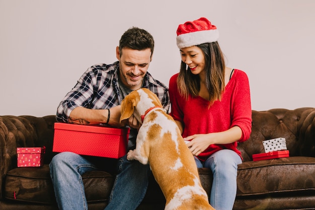 Lächelnde Paare auf Couch mit Hund am Weihnachten