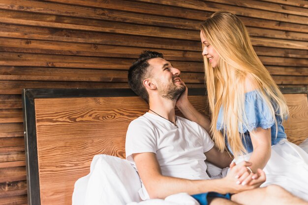 Lächelnde Paare, die auf Bett sitzen