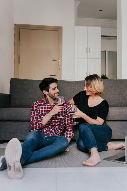 Lächelnde Paare mit Wein an der Couch