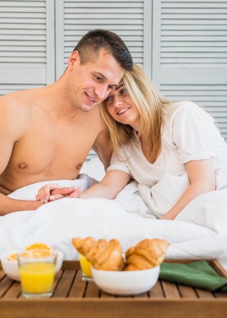 Kostenloses Foto lächelnde paarhändchenhalten im bett nahe frühstück an bord