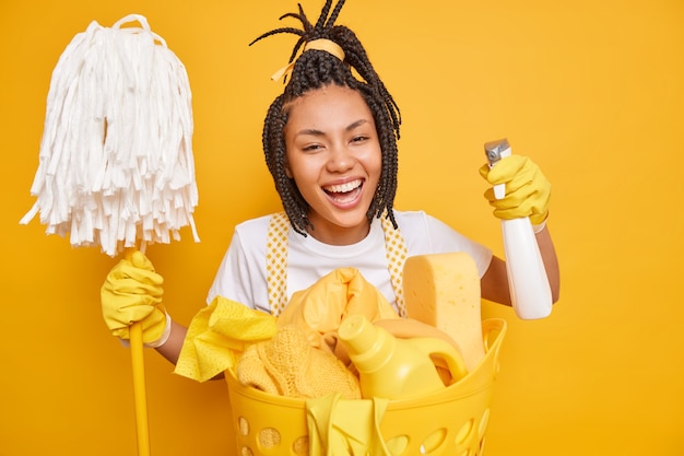 Lächelnde positive Hausfrau mit Dreadlocks hält Mop