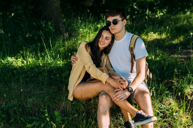 Kostenloses Foto lächelnde romantische paare, die auf grünem gras sitzen