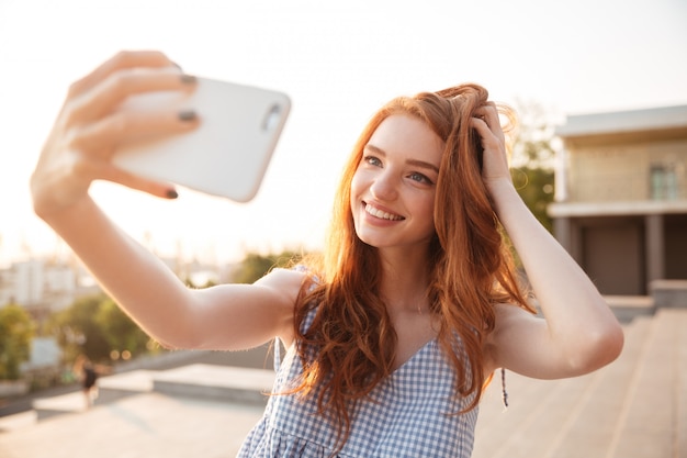 Kostenloses Foto lächelnde rothaarige frau mit langen haaren, die ein selfie nehmen