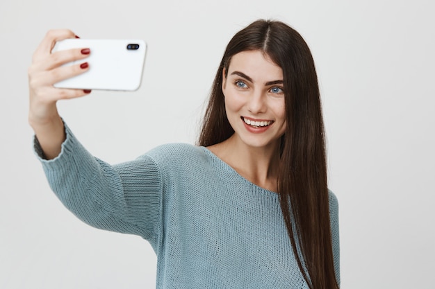 Lächelnde schöne Frau, die selfie auf Smartphone nimmt