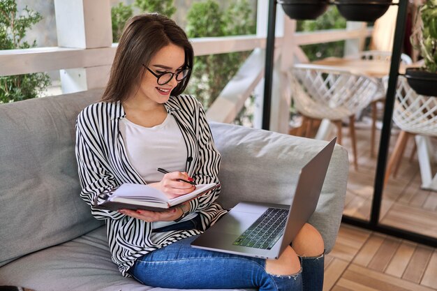 Lächelnde schöne Frau, die zu Hause mit Laptop lernt.