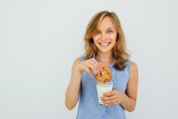 Lächelnde schöne Frau Dunking Cookie in Milch