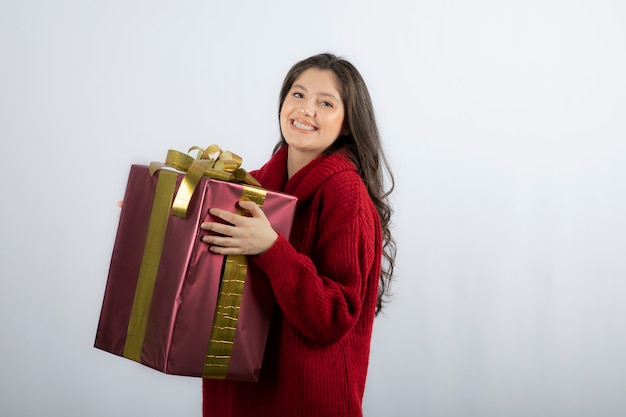 Lächelnde schöne junge Frau, die eine Weihnachtsgeschenkbox hält.