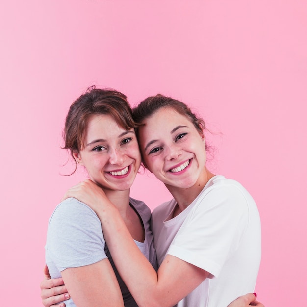 Lächelnde Schwester zwei, die gegen rosa Hintergrund sich liebt